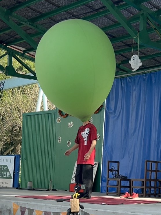 大道芸人GEN(ジェン)が宇都宮動物園 大道芸イベントでジャイアントバルーンを頭にかぶりパフォーマンスを行っている